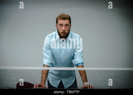 Junger gutaussehender Mann mit Bart, der Tischtennis spielt Stockfoto