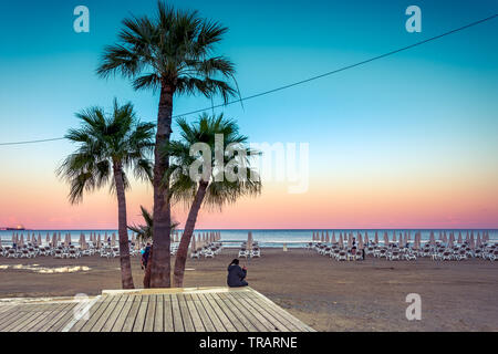 Palmen und Liegestühle am Sandstrand von Larnaca, Zypern Stockfoto