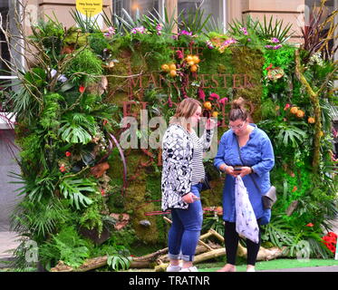 Von Manchester King Street Festival und Flower Show eröffnet für zwei Tage am 1. Juni 2019, Performance, Musik und kreative Blumenarrangements. Das Festival ist zu einem Retro 60er's Theme. Eine Frau und ein Mädchen stehen vor der florale Zeichen bei der Bekanntgabe der Flower Show am südlichen Ende der King Street. Stockfoto