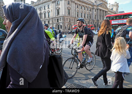 Frau mit Kopftuch und Radfahrer Radfahren in hektischen Verkehr nach der Arbeit reiten Fahrräder in der Nähe von Houses of Parliament Square Westminster London KATHY DEWITT Stockfoto