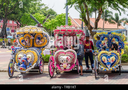 Malakka, Malaysia - April 21,2019: Die farbenfroh gestalteten Rikschas sind Parkplätze in Dutch Square Malacca warten auf Kunden. Stockfoto