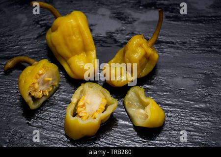 Gebeizt Golden griechische Paprika, pepperoncini oder Friggitelli (süßen italienischen Chili) auf Naturstein Hintergrund. Capsicum annuum. Stockfoto