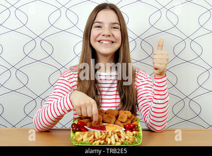 Happy Teenager mit leckeren Chicken Nuggets und Daumen hoch Stockfoto