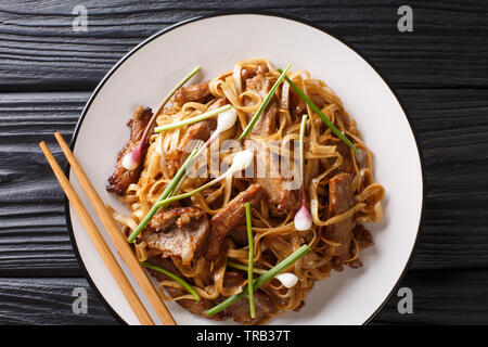 Beef Chow Fun Nudeln (Pan-Fried Ho Fun) kantonesische Gerichte Nahaufnahme auf die Platte auf dem Holztisch. horizontal oben Ansicht von oben Stockfoto