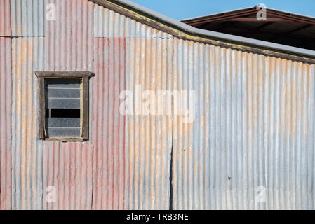 Die seitliche Ansicht einer alten verzinktes Eisen, Halle oder Scheune auf dem Bauernhof im Nordwesten von New South Wales, Australien, einschließlich ein kleines Fenster mit Lüftungsschlitzen Stockfoto