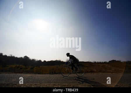 Radfahrer vorbei an einer wunderschönen kleinen Pfad in der Natur in einem weiten, offenen Landschaft genießen das Wetter und die Schönheit um Sie herum Stockfoto