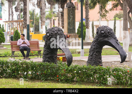 Mann sitzt auf der Bank hinter Vogel Skulpturen an Federico Villarreal Park in Barranco Viertel von Lima, Peru. Stockfoto