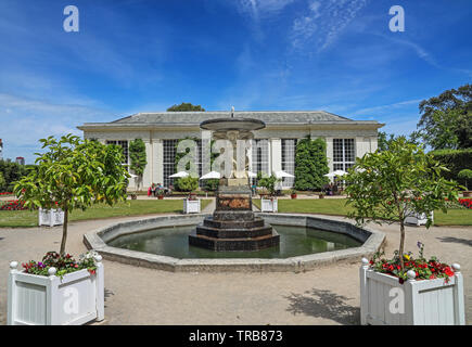 Brunnen im Italienischen Garten am Mount Edgcumbe Park Cornwall. Die Orangerie Cafe mit Sonnenschirme außerhalb im Hintergrund Sommer 2019 Stockfoto