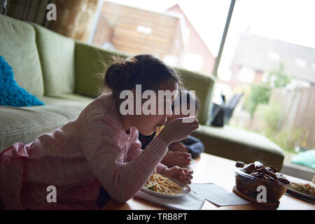 Vater helfen, seine netten jungen Sohn sein Mittagessen im Wohnzimmer zu essen Stockfoto