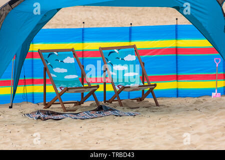 Dekorative Liegestühle vor dem Windbreak Windbreak Windbreaker am Bournemouth Beach, Dorset UK im Juni Stockfoto