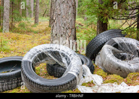 Alte gebrauchte Autoreifen links, im Wald gedumpten, ökologische Konzept Stockfoto
