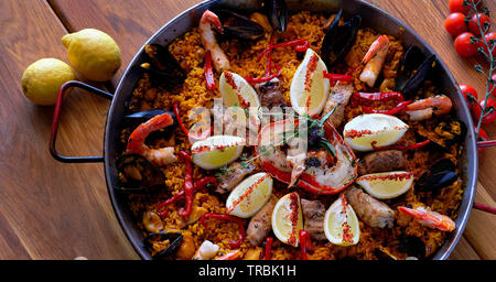 Leckere spanische Paella, Ansicht von oben. Mit stör Heilbutt-filet gekochte, geschälte Garnelen, Tintenfisch, Muscheln und Hummer mit Zitrone Stockfoto