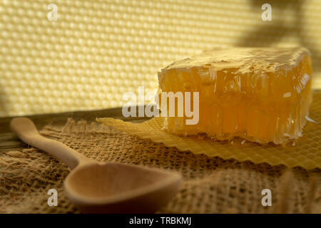 Block der natürlichen honey comb mit gesunden frischen Honig neben einem Löffel aus Holz, auf einem Platz der rustikale hessische Tuch mit Kopie Raum Stockfoto