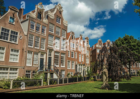 Typische Häuser und grünen Garten des Begijnhof, einem mittelalterlichen Gemeinschaft in Amsterdam. Stadt mit riesigen kulturelle Aktivität, Kanäle und Brücken in den Niederlanden. Stockfoto