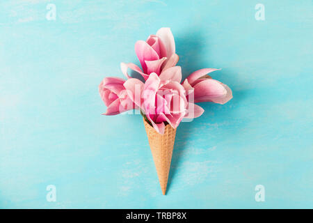 Eis mit rosa Magnolia Blumen Blumenstrauß auf blauem Hintergrund. Minimale Feder Konzept. Flach. top anzeigen. Hochzeit Hintergrund Stockfoto