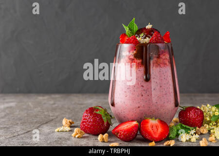 Erdbeere Chia Samen Pudding mit Schokolade, frische Beeren, Müsli, elderflowers und Minze für gesunde leckere Frühstück auf konkreten Hintergrund Stockfoto