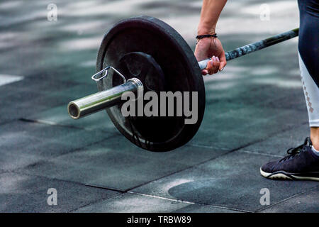 Crossfit Frau vorbereiten für Ihre weightlifting Workout mit einem schweren Hantel Stockfoto