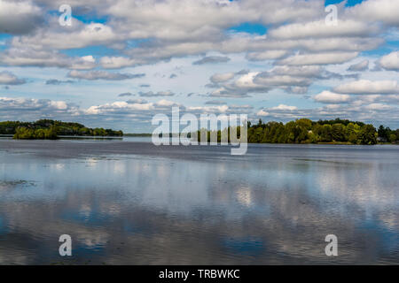 Ferienhaus See mit placid Lake, Cloud Reflexion über Wasser, blauer Himmel mit weißen flauschigen Wolken und grünen Wald Stockfoto