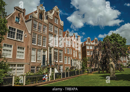 Doppelhaushälfte typischen Häusern und grünen Garten des Begijnhof in Amsterdam. Stadt mit riesigen kulturelle Aktivität, Kanäle und Brücken in den Niederlanden. Stockfoto