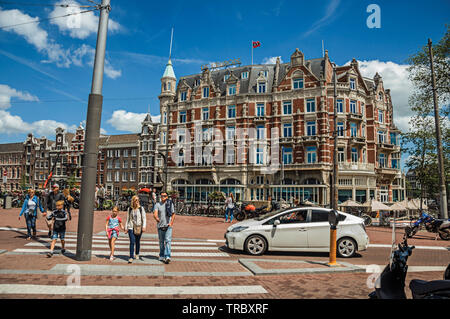 Straße mit typischen Backsteinbauten, Menschen und Radfahrer vorbei in Amsterdam. Stadt mit riesigen kulturelle Aktivität, Kanäle und Brücken in den Niederlanden. Stockfoto