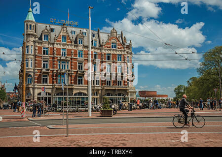Straße mit typischen Backsteinbauten, Menschen und Radfahrer vorbei in Amsterdam. Stadt mit riesigen kulturelle Aktivität, Kanäle und Brücken in den Niederlanden. Stockfoto