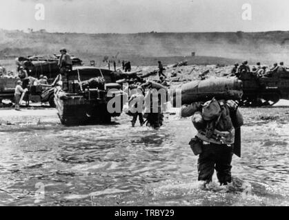 American assault Truppen mit voller Ausrüstung bewegen Sie auf Omaha Beach hinter schweren Material einschließlich der Hälfte - Titel und DUKWS. Rauch im Hintergrund ist von Naval geschützfeuer Unterstützung bei der Landung. Der Normandie. Juni 6, 1944. Stockfoto