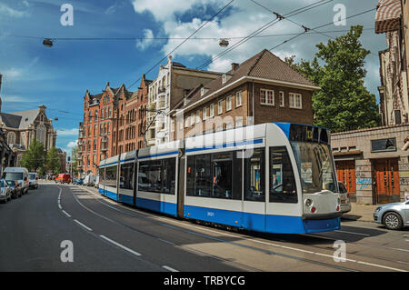 Straße mit blauer Himmel, alte Gebäude und die Straßenbahn in Amsterdam. Stadt mit riesigen kulturelle Aktivität, Kanäle und Brücken in den Niederlanden. Stockfoto