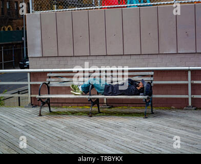 Obdachlosen schläft auf der Bank an der Strandpromenade von Coney Island, Brooklyn Stockfoto