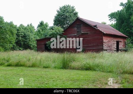 Eine verwitterte rote Scheune sitzt in einem grünen Feld rot am George Washington Birthplace National Monument, Westmoreland County, VA, USA. Stockfoto