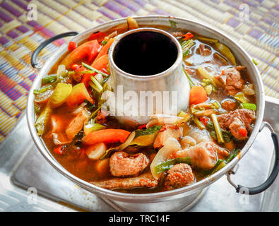 Spicy Chicken Soup Kräuter und Gewürze in den heißen Topf auf Fach asiatische, thailändische Speisen serviert. Stockfoto