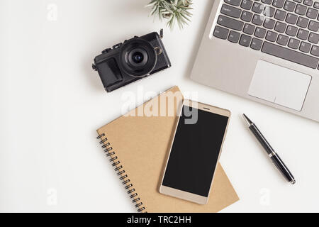 Kreative flach Foto von Arbeitsbereich Schreibtisch mit Laptop, leere Kopie Raum Smartphone und Kamera auf weißem Hintergrund. Mockup Leerzeichen smartphone Stockfoto