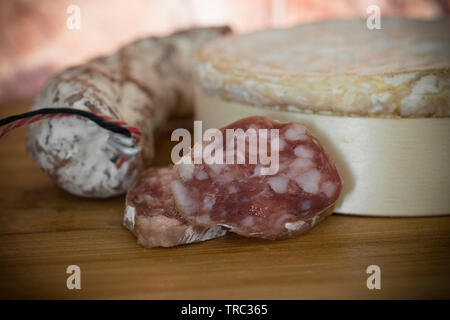 Eine Nahaufnahme von einem weichen französischer Käse und Würstchen auf einem Holzbrett Schnitt Stockfoto