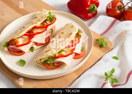 Hausgemachte italienische Piadina auf einem weißen Teller mit Gemüse Tomaten und Paprika auf weißem Hintergrund. Italienische Küche. Ansicht von oben, kopieren. Flach Stockfoto