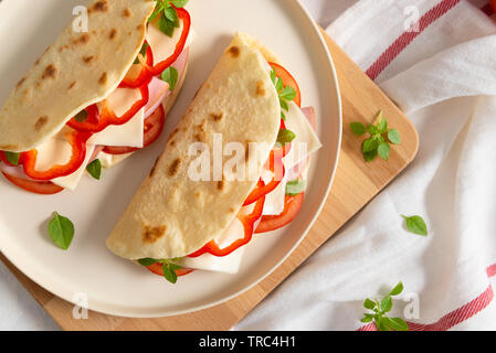 Hausgemachte italienische Piadina auf einem weißen Teller mit Gemüse Tomaten und Paprika auf weißem Hintergrund. Italienische Küche. Ansicht von oben, kopieren Platz für Text. fla Stockfoto