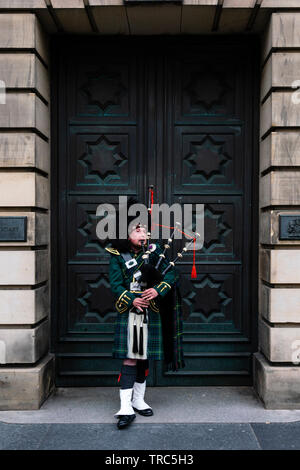 Scottish Piper spielt Dudelsack auf ausserhalb von Edinburgh Royal Mile High Court in der Altstadt von Edinburgh, Schottland, Großbritannien Stockfoto