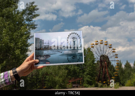 Tour Guide hält ein Archiv Foto vor dem Riesenrad in der verlassenen Stadt Pripyat, Sperrzone von Tschernobyl, Ukraine Stockfoto