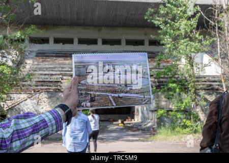 Tour Guide mit Foto von Avanhard Stadion in der verlassenen Stadt Pripyat, Sperrzone von Tschernobyl, Ukraine Stockfoto