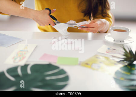Junge brünette Frau erstellen mit Schere ihr Feng Shui wünschen Karte Stockfoto