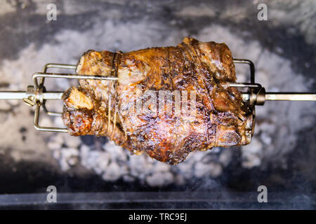 Lecker Lammkeule Kochen am Spieß rotisserie über glühende Kohlen. Stockfoto