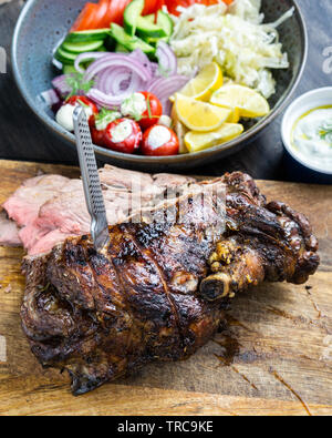 Lecker Lamm bein Braten auf eine Rotisserie mit frischen griechischen Salat und Soße für Souvlaki wraps serviert gekocht. Stockfoto