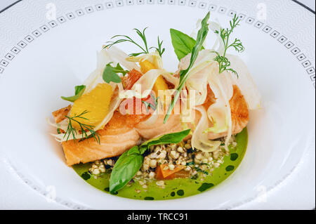 Bio Lachs rot Fischfilet mit frischen grünen Salat treibt, Buchweizen Sprossen und Sauce close-up auf weiße Platte isolierten gekocht Stockfoto