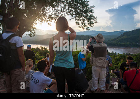 Touristen beobachten Sie den Sonnenuntergang am Mount Phousi, einem 100 m hohen Hügel im Zentrum der Altstadt von Luang Prabang, Lao PRD (Laos). Stockfoto