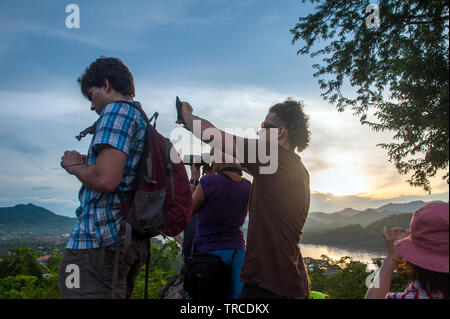 Touristen beobachten Sie den Sonnenuntergang am Mount Phousi, einem 100 m hohen Hügel im Zentrum der Altstadt von Luang Prabang, Lao PRD (Laos). Stockfoto