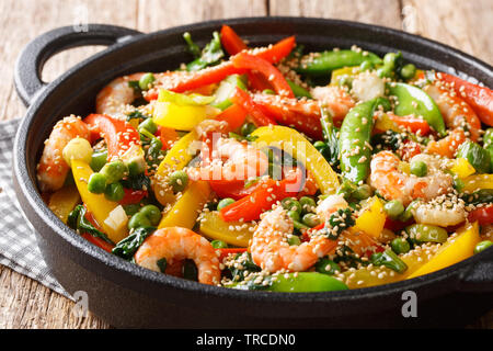 Stir Fry von Garnelen mit Paprika, Zwiebeln, Kräuter, Hülsen, Erbse, Sesam close-up in einer Pfanne auf dem Tisch. Horizontale Stockfoto