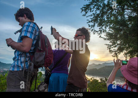 Touristen beobachten Sie den Sonnenuntergang am Mount Phousi, einem 100 m hohen Hügel im Zentrum der Altstadt von Luang Prabang, Lao PRD (Laos). Stockfoto