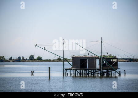 Die traditionelle Fischerei Hütte auf Stelzen mit hängenden Netzen in Comacchio Tal, Emilia Romagna, Italien. Das Fischerdorf liegt in einer Lagune, surro gelegen Stockfoto