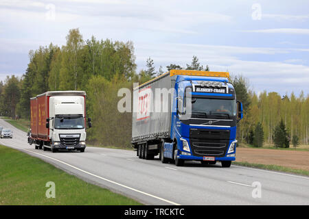 Salo, Finnland - 10. Mai 2019: Blaue Volvo FH truck Vor Sattelschlepper überholt Lkw ziehen voll Anhänger auf Landstraße im Süden Finnlands. Stockfoto