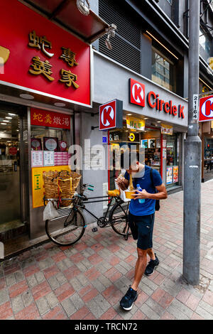 Ein junger Mann auf der Straße Essen Nudeln, Hongkong, China Stockfoto