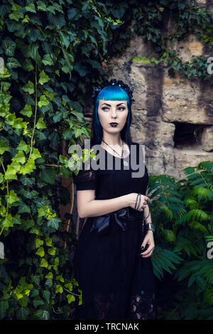 Schöne Goth Girl mit hellen blauen Haare stehen im Grünen Efeu. Am Vorabend von Halloween Stockfoto