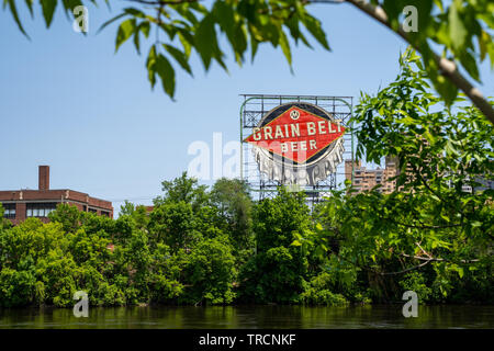 Minneapolis, Minnesota - Juni 2, 2019: Iconic Korn Gürtel Bier Schild in der Innenstadt von Minneapolis, am Ufer des Mississippi, umrahmt von FOILAGE Stockfoto